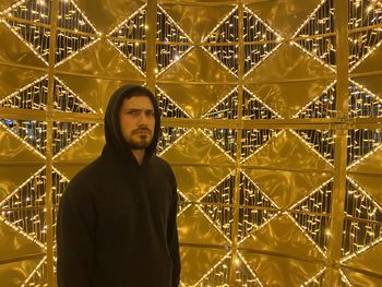 Portrait of young man standing against illuminated lights