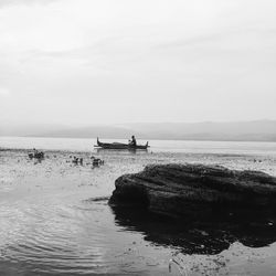 Men sitting on boat in sea against sky