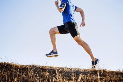 Full length of woman exercising on field against clear sky