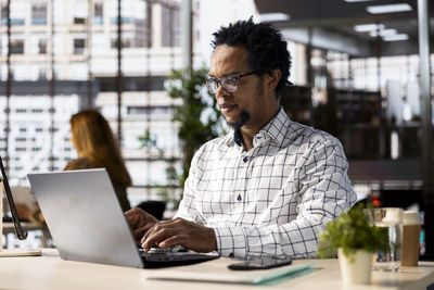 Side view of young man using laptop at office