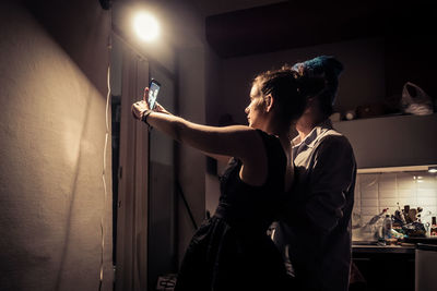 Man standing by illuminated lamp at night