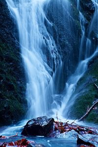 Water spray below small waterfall on mountain stream, water is falling over mossy boulder. the spray 