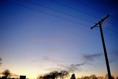 Low angle view of electricity pylon against cloudy sky