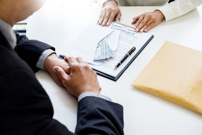 High angle view of client offering money to businessman at desk in office