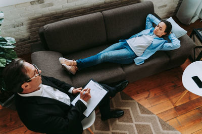 High angle view of men sitting on sofa at home