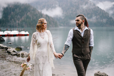 A happy couple in love and married embrace in nature by the lake and the misty mountains