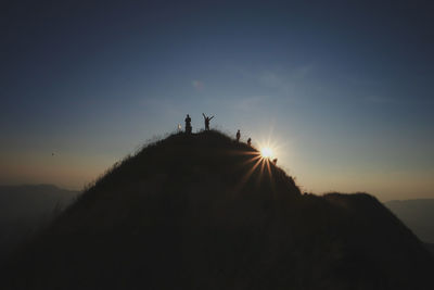 Silhouette people on mountain against sky during sunset