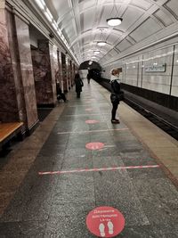 Rear view of man walking on illuminated underground walkway