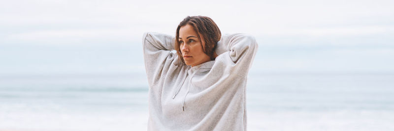 Side view of young woman standing against sea