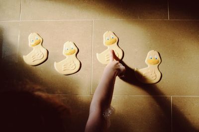 Cropped image of girl pointing at duck toy stuck on wall