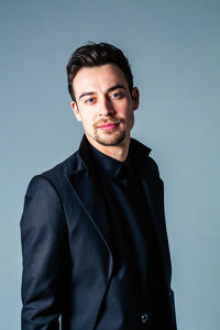 Portrait of young man standing against blue background