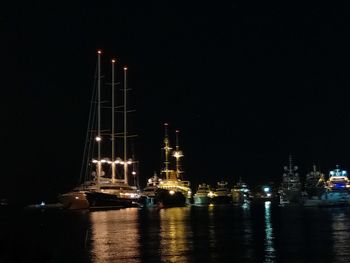 Illuminated city by sea against sky at night