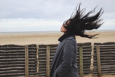 Side view of woman with tousled hair at beach
