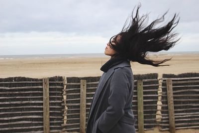 Silhouette of woman standing by sea against cloudy sky