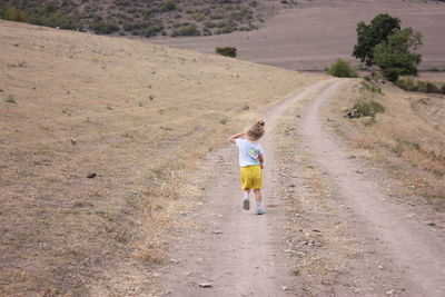 Rear view of woman walking on dirt road