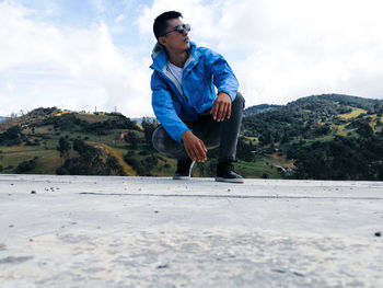 Young man standing on mountain against sky