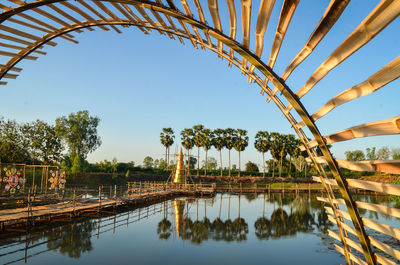 Reflection of palm trees in lake against sky