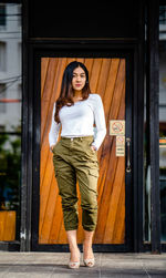 Portrait of young woman standing against door