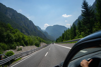 Car on road by mountains against sky