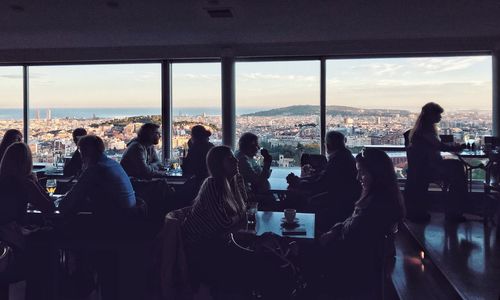 People sitting at cafe in city against sky