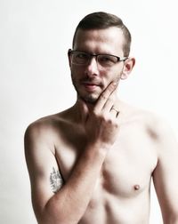 Portrait of shirtless man wearing eyeglasses against white background