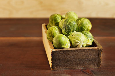 Wooden box with green brussel sprouts on table , brassica oleracea