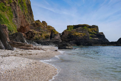 Rock formations on beach against sky