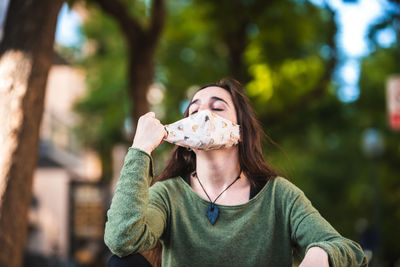 Young woman wearing mask sitting outdoors