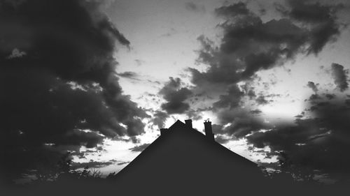 Silhouette of building against cloudy sky