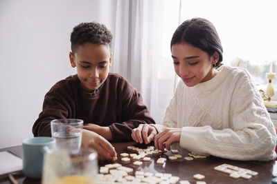 Girl and boy playing scrabble at dining table