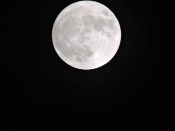 Low angle view of full moon against dark sky