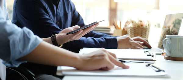 Rear view of man using mobile phone while sitting on table