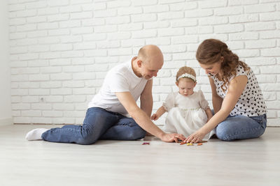 Full length of family sitting on sofa at home