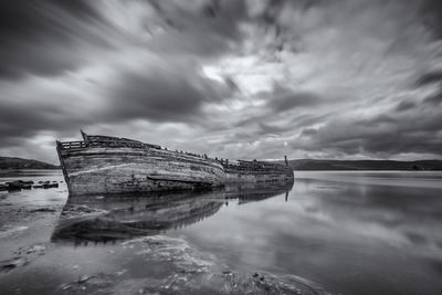 Abandoned boat in sea against sky