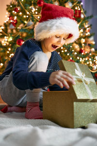 A cute boy opens a gift near the new year tree. christmas miracle