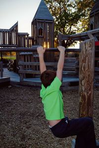 Boy hanging on monkey bar at playground