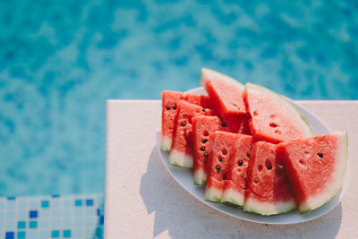Close-up of watermelon in plate by swimming pool