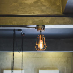 Illuminated pendant light hanging from ceiling at home