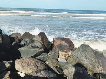 Scenic view of rocks on beach against sky