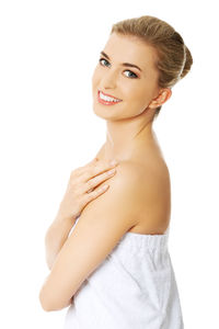 Portrait of smiling woman wrapped in towel against white background