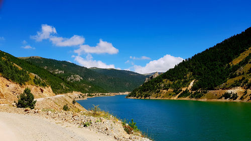 Scenic view of sea and mountains against blue sky