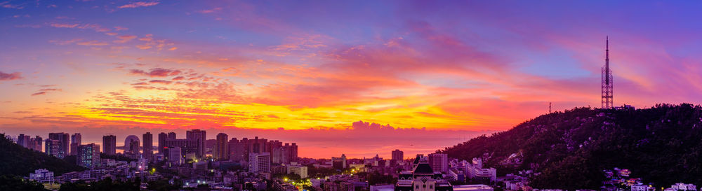 Panoramic view of buildings against cloudy sky during sunset