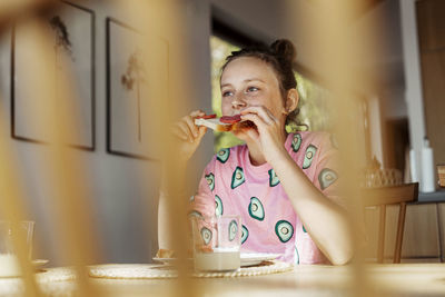 Girl sitting at table and eating sandwich