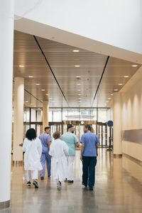 Rear view of male and female doctors walking in hospital