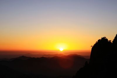 Scenic view of silhouette mountains against orange sky