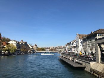 River amidst buildings in city against clear blue sky