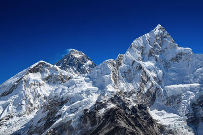 Scenic view of snowcapped mountains against blue sky