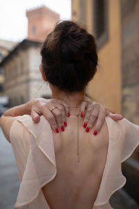 Rear view of woman standing against buildings in city