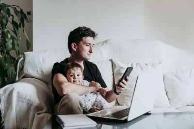 Man using mobile phone while sitting on sofa at home