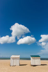 Beach huts at beach against blue sky